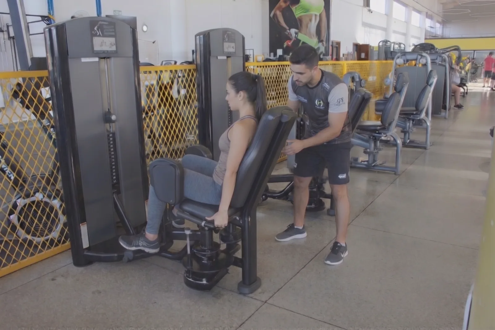 Professor acompanhando aluno durante o treino na área de musculação
